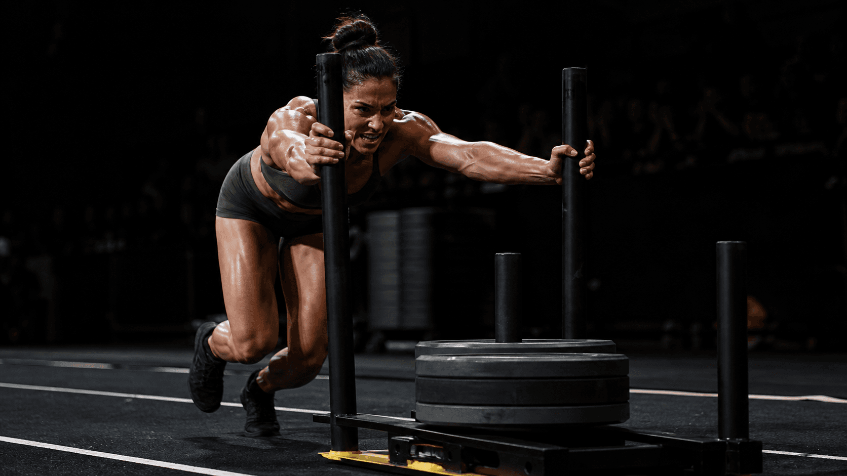 Female athlete driving a heavy sled forward